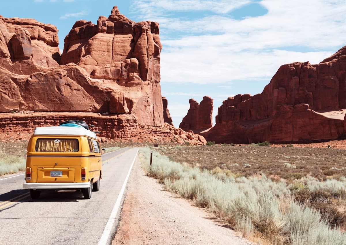 Camper van traveling between red rock formations